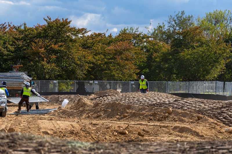 WASHINGTON, DC - OCTOBER 24: Workers build a fence as trucks unload debris and soil  from the demolition of the White House's East Wing at East Potomac Golf Course on October 24, 2025 in Washington, DC. The demolition is part of U.S. President Donald Trump's plan to build a multimillion-dollar ballroom on the eastern side of the White House. (Photo by Tasos Katopodis/Getty Images)