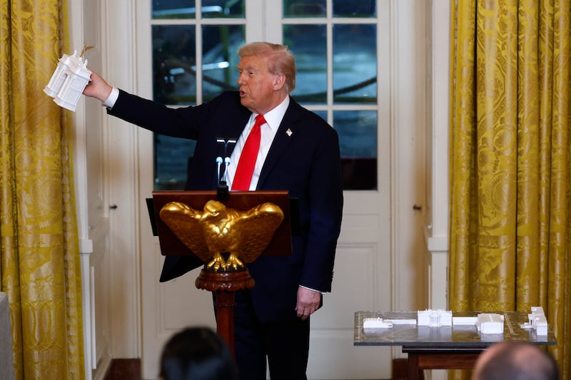 WASHINGTON, DC - OCTOBER 15: U.S. President Donald Trump holds models of an arch as he delivers remarks during a ballroom fundraising dinner in the East Room of the White House on October 15, 2025 in Washington, DC. Trump hosted organizations and individuals for a fundraising dinner for the new $250 million ballroom addition currently under construction at the White House. (Photo by Kevin Dietsch/Getty Images)