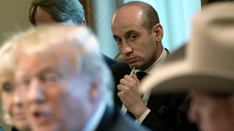U.S. President Donald Trump speaks as Stephen Miller (C) listens.