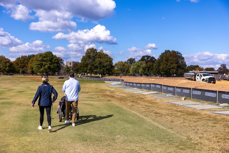 WASHINGTON, DC - OCTOBER 24: Golfers play hole five as trucks unloads debris and soil from the demolition of the White House's East Wing at East Potomac Golf Course on October 24, 2025 in Washington, DC. The demolition is part of U.S. President Donald Trump's plan to build a multimillion-dollar ballroom on the eastern side of the White House. (Photo by Tasos Katopodis/Getty Images)